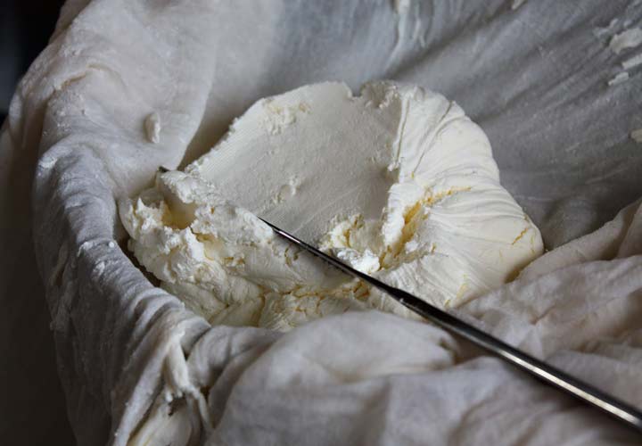 طرز تهیه پنیر خامه ای در خانه - باید پنیر را در پارچه ای بگذارید تا آب پنیر از آن جدا بشود.