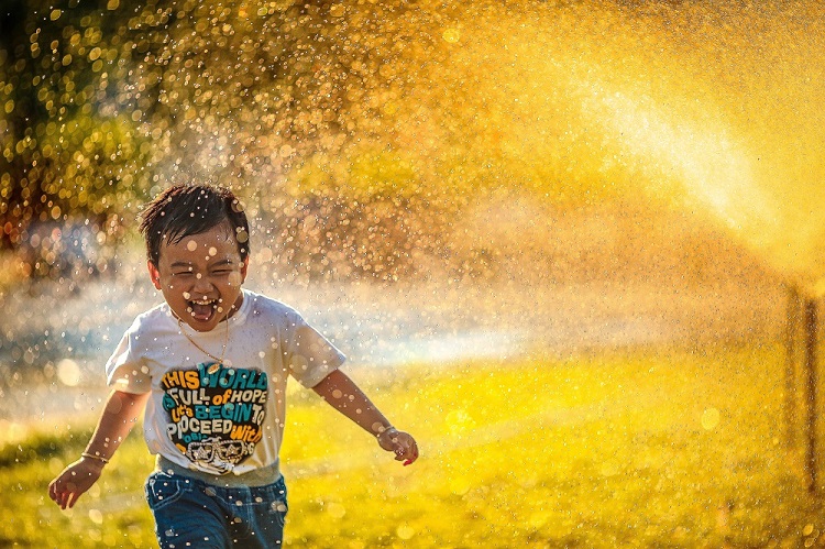 دویدن کودک شاد زیر فواره آب