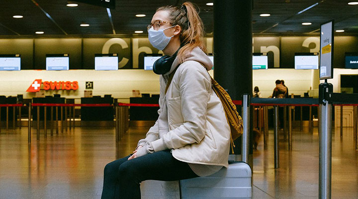 زنی نشسته به‌روی چمدان - پیشگیری از کرونا در سفر