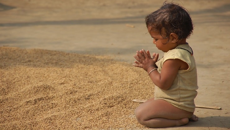 کودک خردسال نشسته و دستها را به حالت دعا در پیش گرفته - تأثیر قدردانی