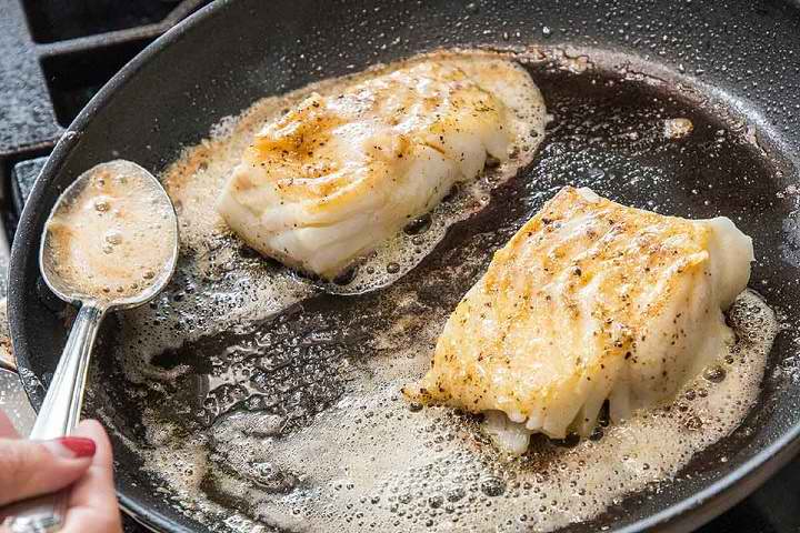 ریختن کره آب شده روی ماهی در حال سرخ شدن