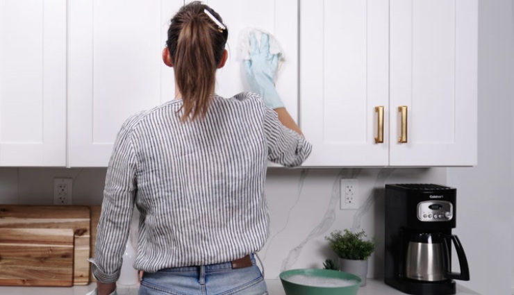 زنی در حال تمیز کردن کابینت آشپزخانه