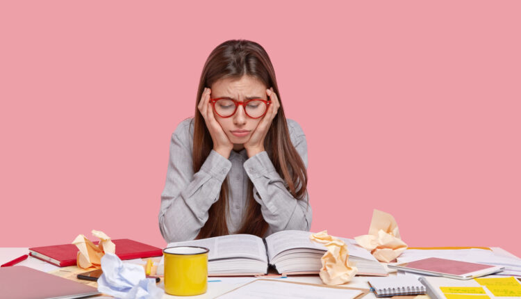 دختر عینکی در حال درس خواندن روی میز شلوغ