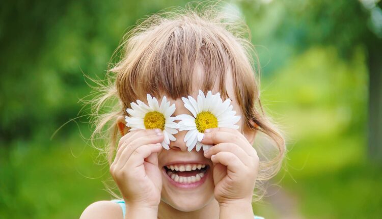 گل بابونه روی چشم های دختر بچه خندان