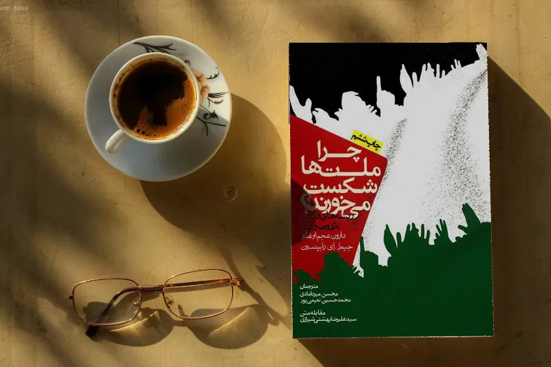 چرا ملت‌ها شکست می‌خورند دارون عجم‌اوغلو و جیمز رابینسون کنار فنجان چای و عینک